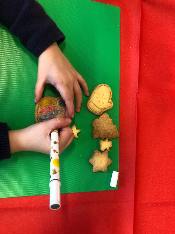 Mains d'enfant décorant un sablé de Noël au feutre alimentaire