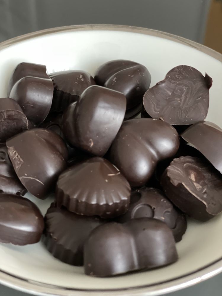 Chocolats noirs moulés en forme de cœur et de coquillage dans une coupelle